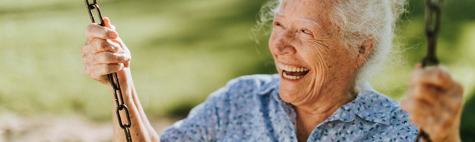 Lachende Seniorin auf einer Schaukel